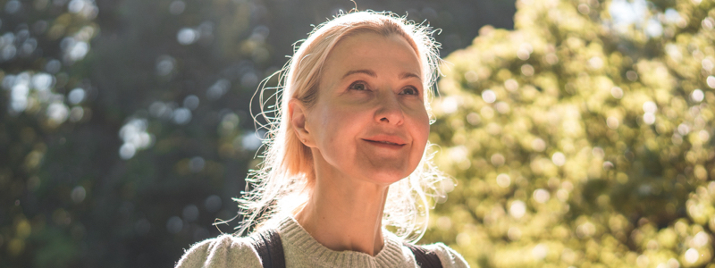 Glad ældre kvinde i naturen i solen lyse skær